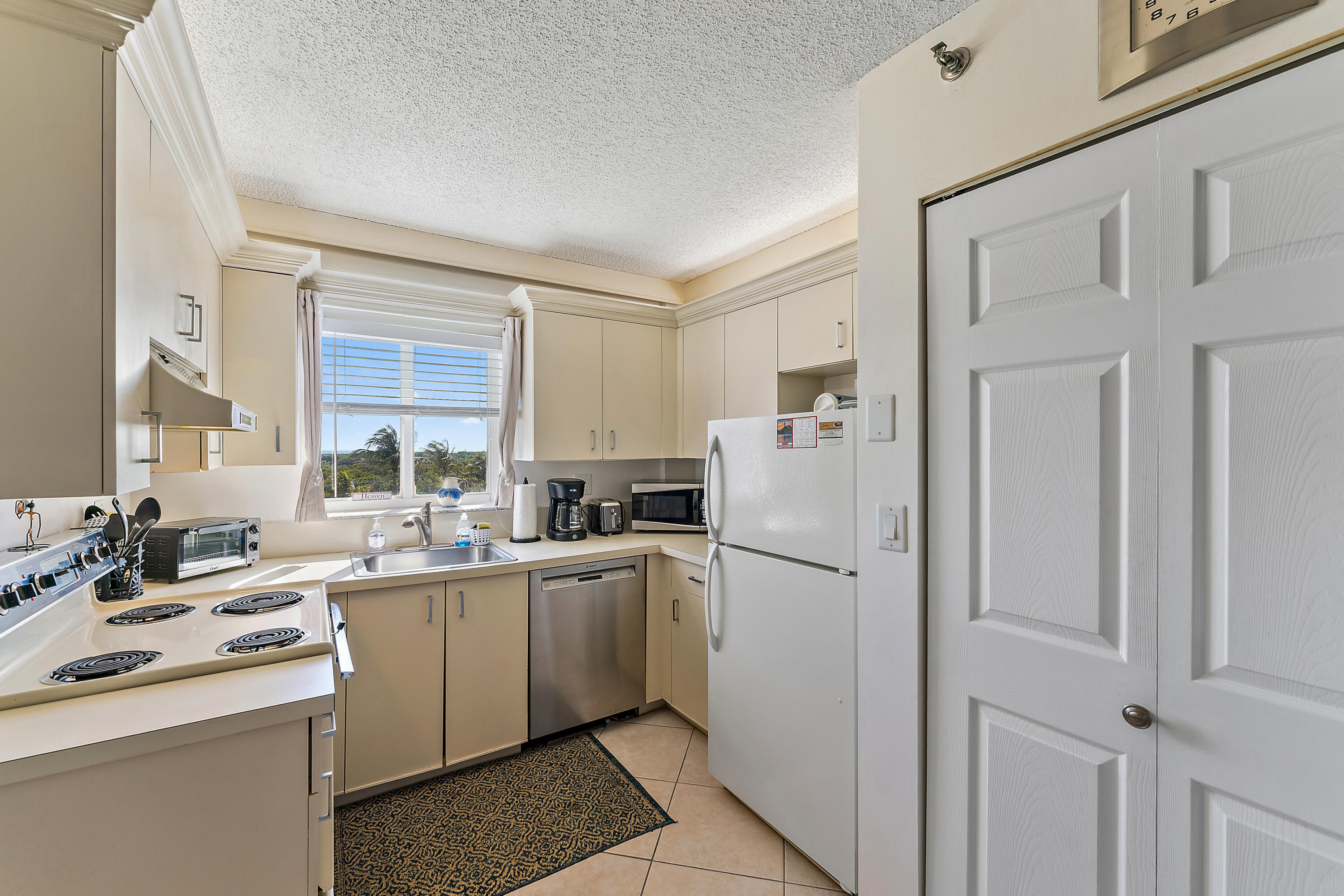 275 Palm Avenue, Unit C503 Jupiter, FL 33477 - Photo 6 of 10 a kitchen with white cabinets and white appliances