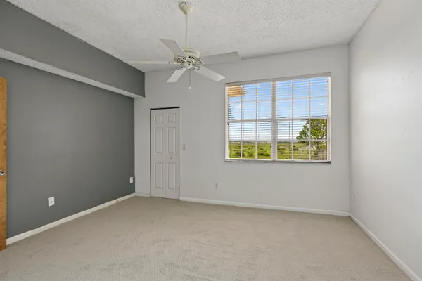 en empty room with windows and chandelier fan