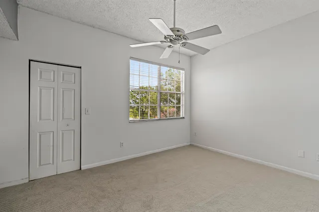 an empty room with windows and fan
