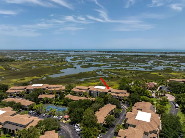 an aerial view of ocean and residential houses with outdoor space