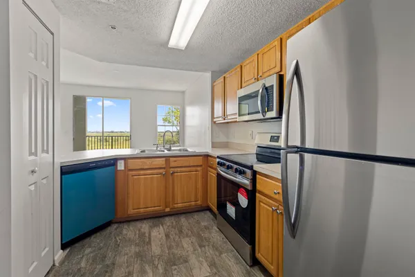 a kitchen with stainless steel appliances granite countertop a refrigerator a sink dishwasher a stove with wooden cabinets