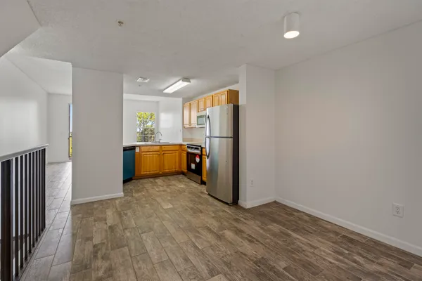a view of a room with wooden floor and refrigerator