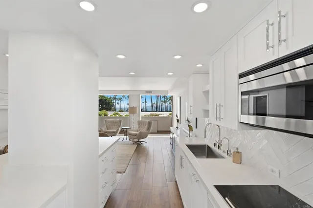 a view of a kitchen with kitchen island stainless steel appliances wooden floor and living room view