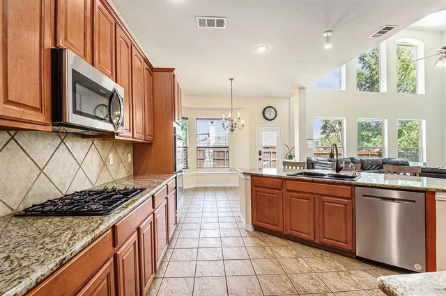 a kitchen with stainless steel appliances granite countertop a stove a sink and a microwave