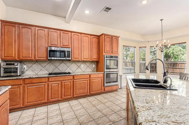 a kitchen with sink a microwave and chairs