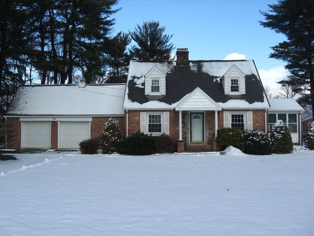 a front view of a house with a yard covered in snow