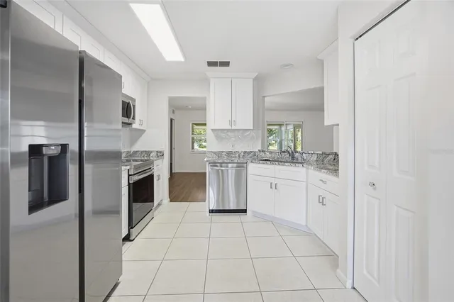 a kitchen with white cabinets and appliances