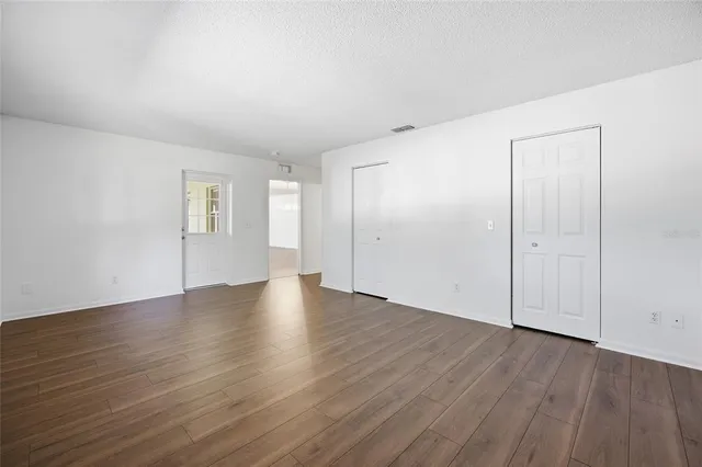 an empty room with wooden floor & windows