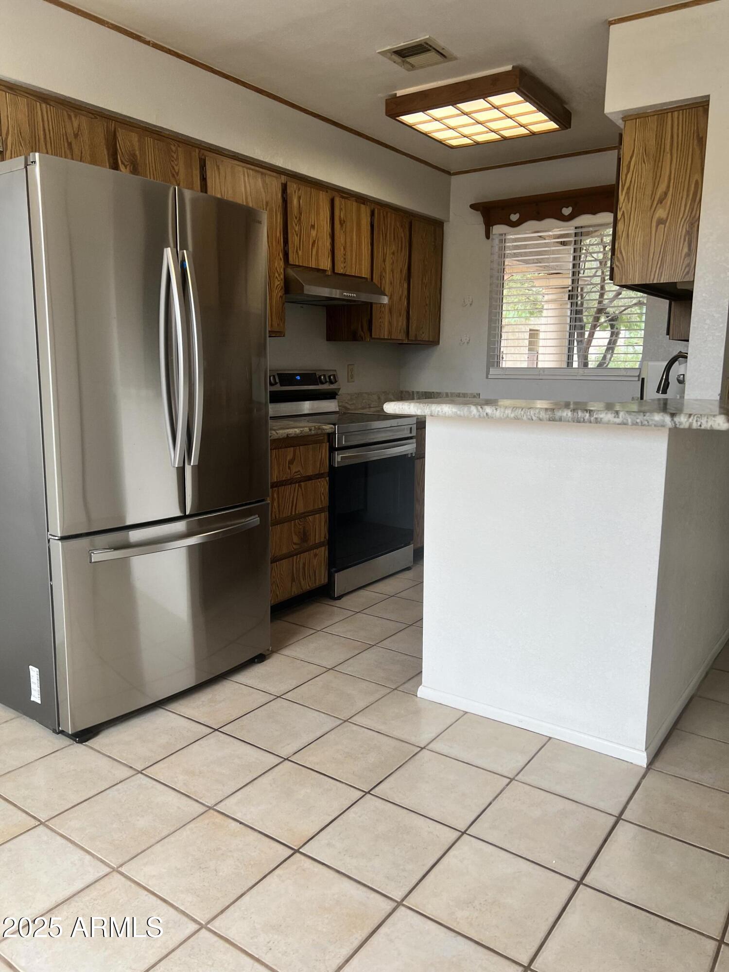 99 North Cooper Road, Unit 136 Chandler, AZ 85225 - Photo 6 of 14 a kitchen with granite countertop a refrigerator and a stove top oven