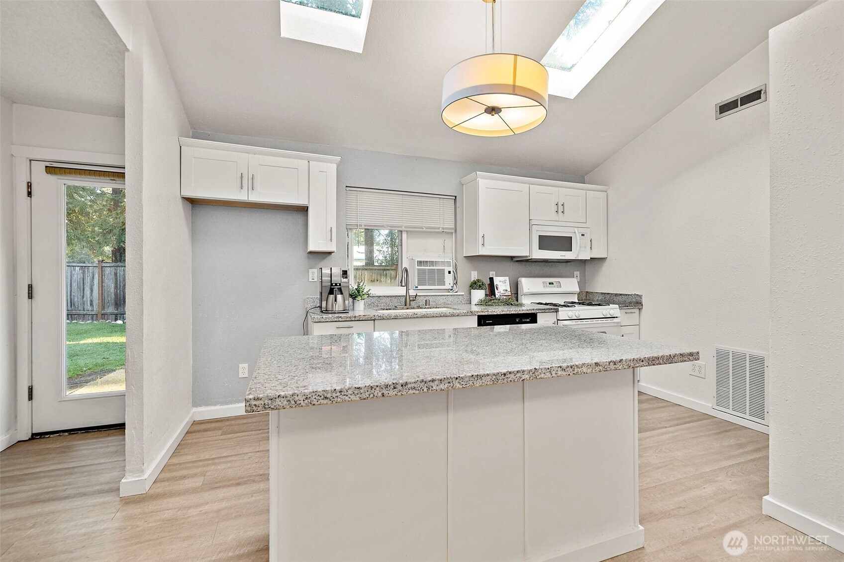 19401 Southeast 267th Street Covington, WA 98042 - Photo 5 of 31 a kitchen with stainless steel appliances granite countertop a sink a stove a refrigerator a microwave oven with white cabinets and wooden floor