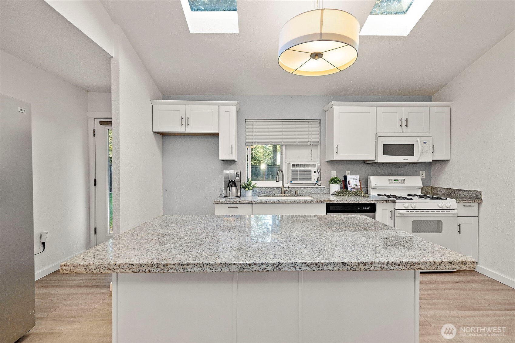 19401 Southeast 267th Street Covington, WA 98042 - Photo 6 of 31 a kitchen with granite countertop stainless steel appliances a sink a stove cabinets and a window