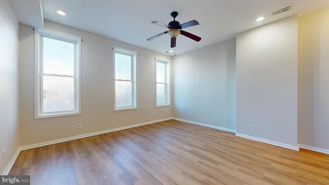 a view of empty room with wooden floor and fan