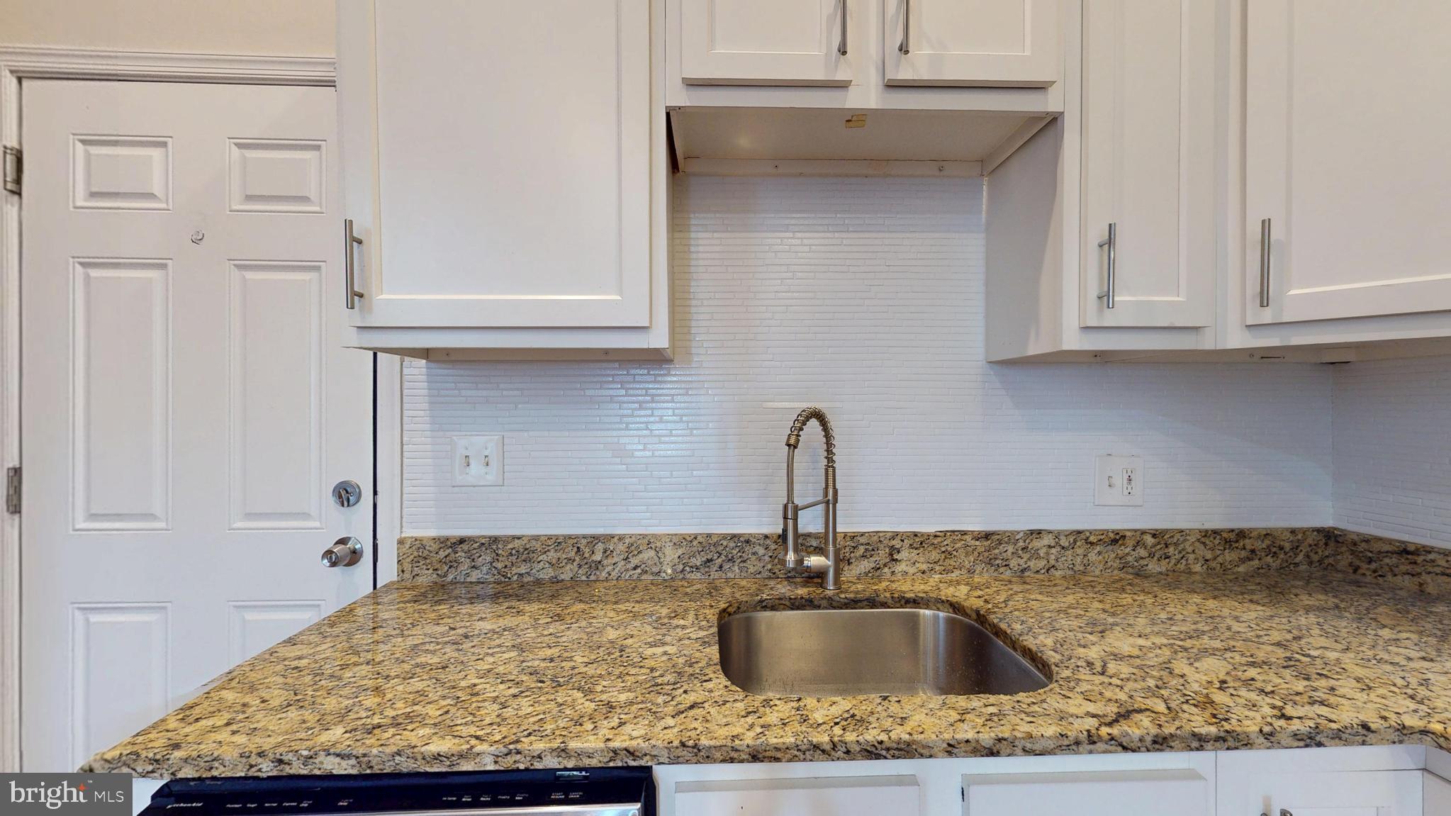 708 North Gilmor Street Baltimore, MD 21217 - Photo 4 of 35 a kitchen with kitchen island a sink granite counter tops and a wooden floor