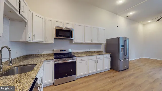 a kitchen with stainless steel appliances granite countertop a refrigerator sink and stove