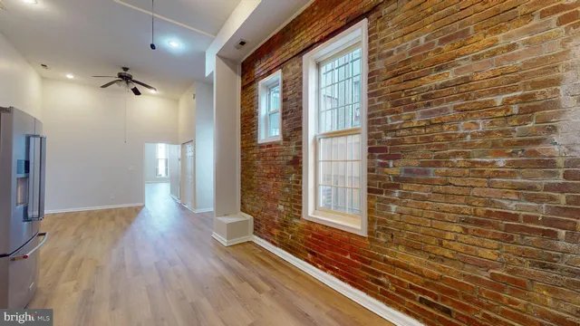 a view of a hallway with wooden floor and a bathroom
