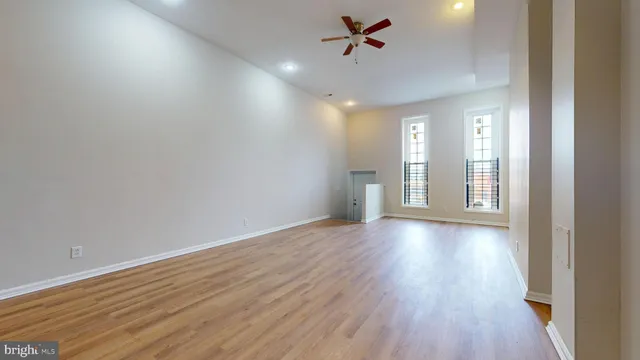 a view of empty room with wooden floor and fan