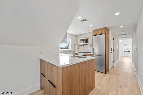 a kitchen with refrigerator a sink and wooden floor