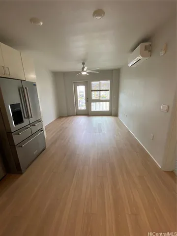 an empty room with wooden floor cabinet and windows