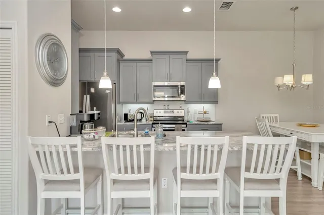 a kitchen with stainless steel appliances a dining table chairs and a refrigerator