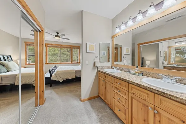 a spacious en suite bathroom with a granite countertop double vanity