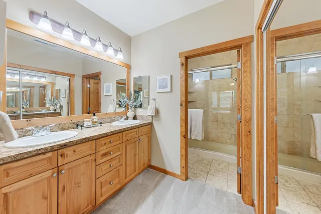 a spacious bathroom with a double vanity sink a mirror and a shower