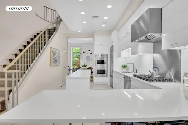 a large white kitchen with wooden floor and stainless steel appliances