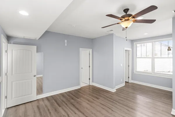an empty room with wooden floor fan and windows