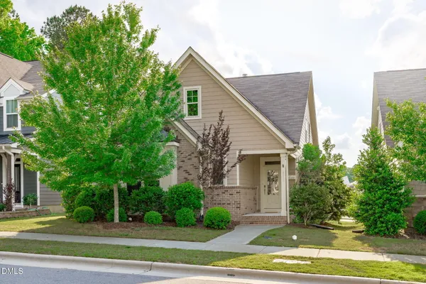 a view of a house with a yard and large tree and plants