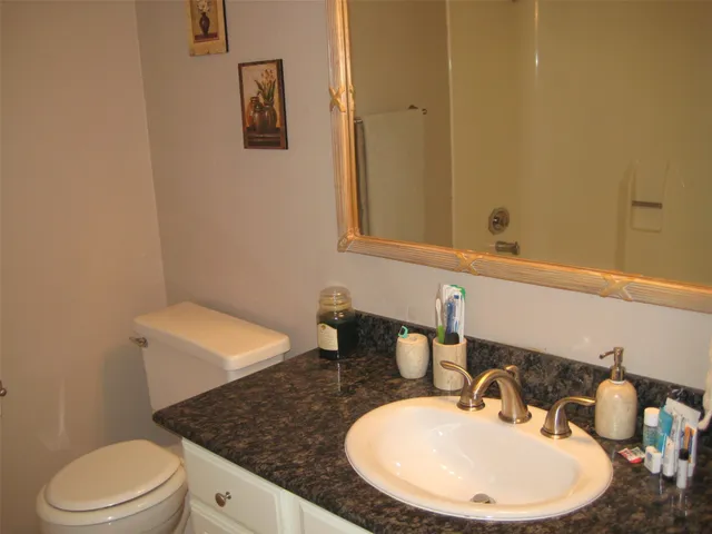 a bathroom with a granite countertop sink and a mirror