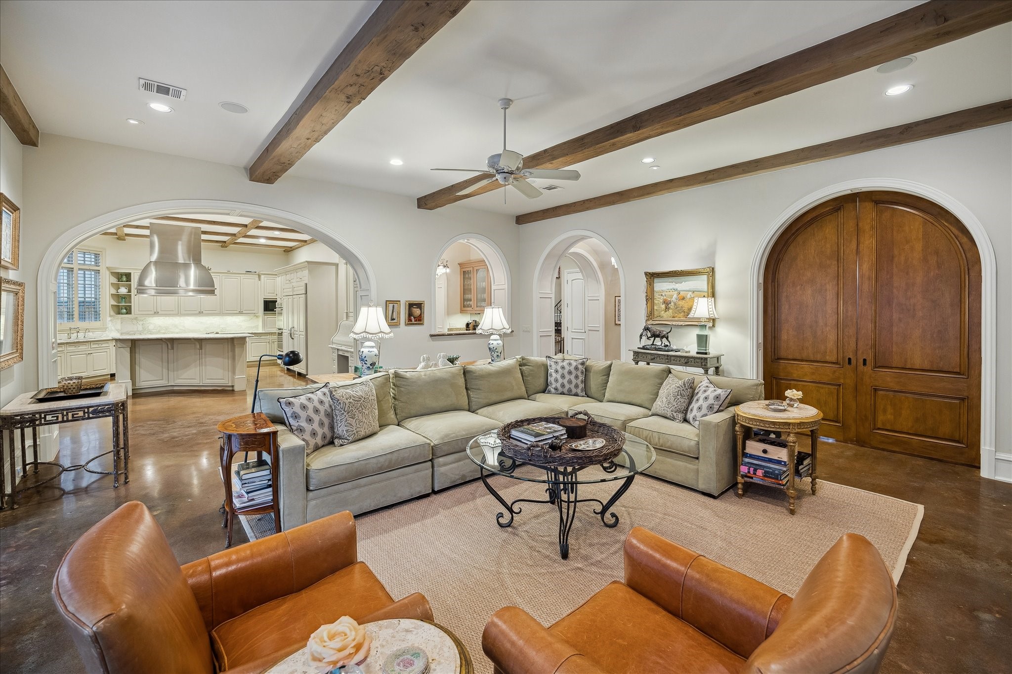 3109 Locke Lane Houston, TX 77019 - Photo 11 of 50 Designed for connection and comfort, this spacious family room seamlessly opens to the kitchen and wet bar. Custom built-ins and a stone fireplace anchor the space, while recessed lighting, neutral tones, and wood-framed French doors with transoms frame sunlit views to the outdoors.