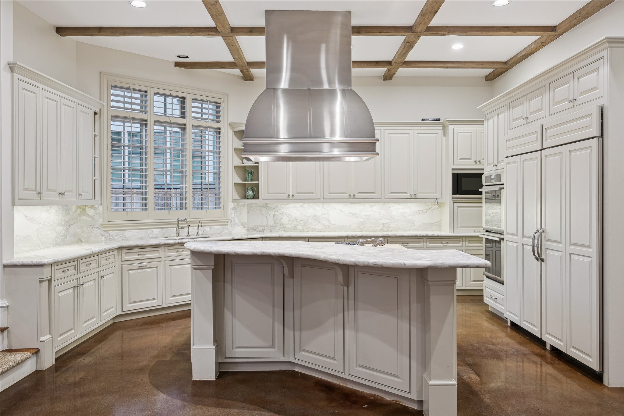 3109 Locke Lane Houston, TX 77019 - Photo 12 of 50 Blending timeless finishes with modern convenience, this kitchen features marble countertops, polished concrete floors, and seamless flow to surrounding gathering spaces. Outfitted with a Wolf gas cooktop, double ovens, two KitchenAid sinks, and a Bosch dishwasher, the space is equally suited for intimate meals or larger-scale entertaining. Extensive storage and direct dining access complete the design.
