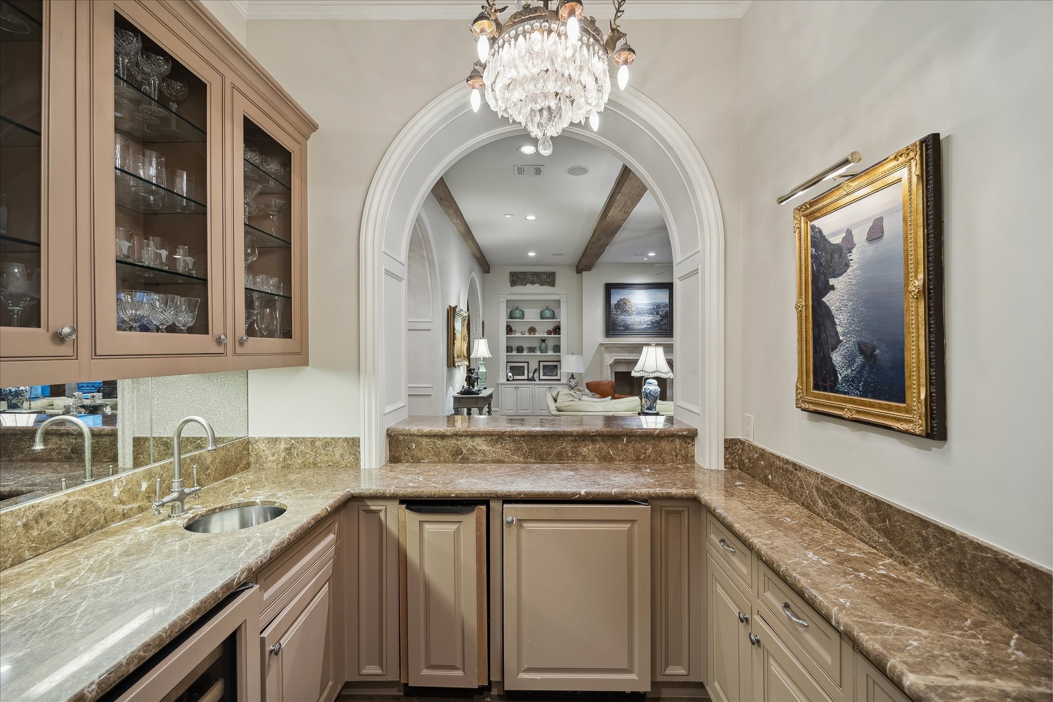 3109 Locke Lane Houston, TX 77019 - Photo 22 of 50 Thoughtfully designed for effortless entertaining, the wet bar features marble countertops, an undermount sink, and a full suite of conveniences including a wine refrigerator, KitchenAid mini refrigerator, and Whirlpool ice maker. Custom upper and lower cabinetry with glass-front display cabinets, under-cabinet lighting, and a mirrored backsplash add both function and a touch of sophistication.