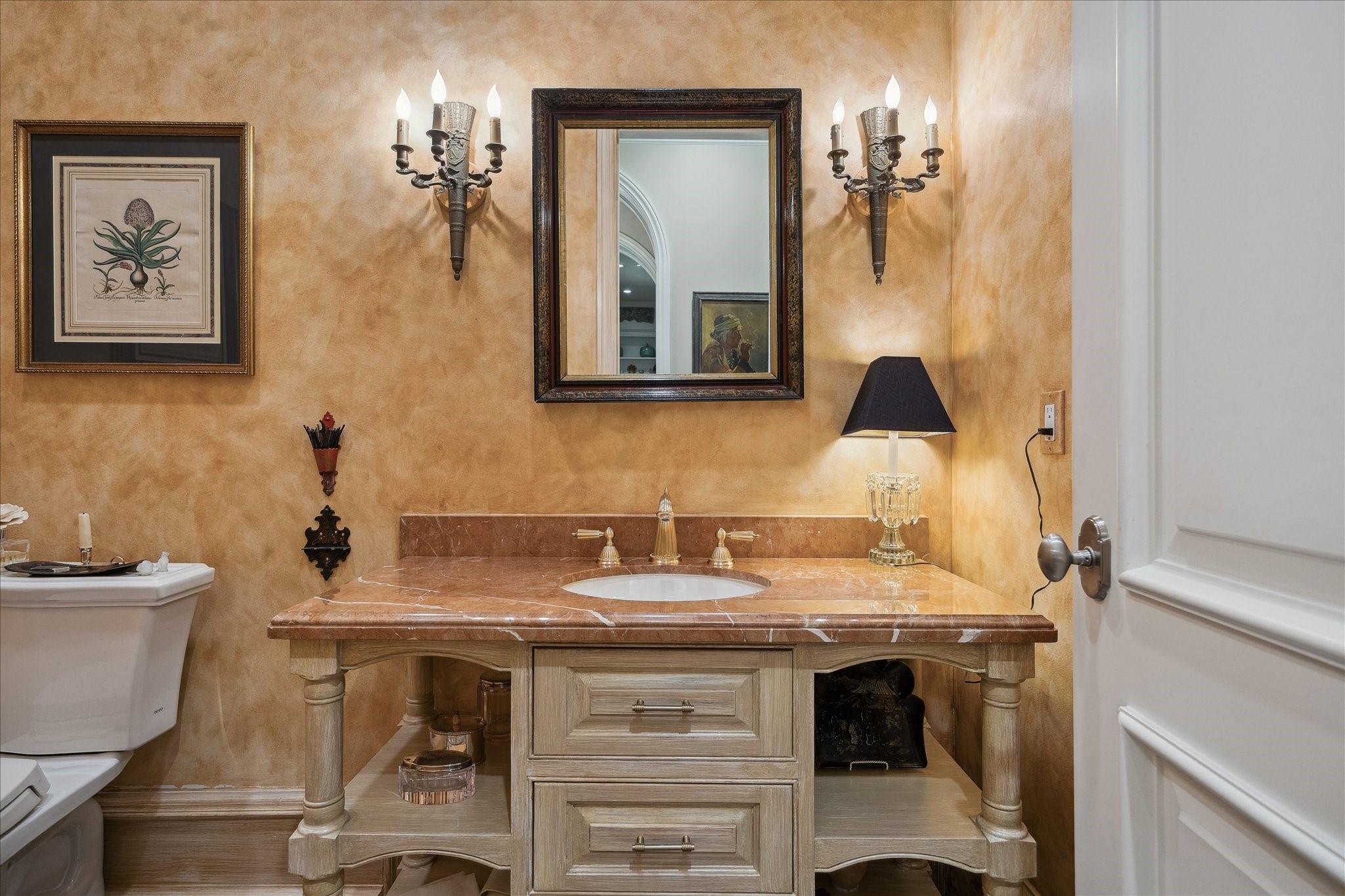 3109 Locke Lane Houston, TX 77019 - Photo 23 of 50 The powder room showcases custom faux-finish painted walls and a marble countertop vanity with an undermount sink. Polished metal faucet and hardware, decorative wall sconces, a framed mirror, and pedestal-style storage combine with elegant trim and molding details for a refined and inviting space.
