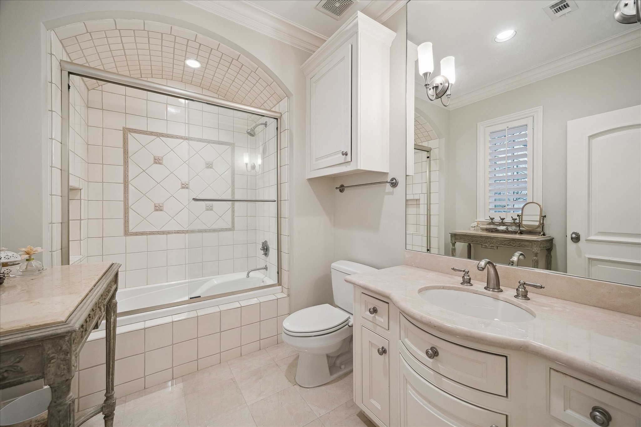 3109 Locke Lane Houston, TX 77019 - Photo 35 of 50 Guest Bathroom No. 3 offers a clean and functional design with a fully tiled tub/shower combination featuring a built-in niche and glass sliding door with brushed nickel hardware. The vanity-style cabinetry provides ample storage with drawers and a ceramic undermount sink, complemented by a large wall mirror, brushed nickel faucet, and hand towel rack for added convenience.