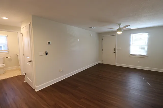 a view of an empty room with wooden floor and a window