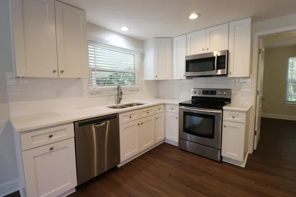 a kitchen with white cabinets stainless steel appliances and wooden floor