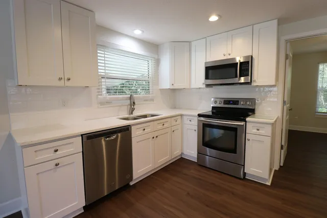 a kitchen with white cabinets stainless steel appliances and wooden floor