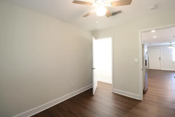 an empty room with wooden floor and a chandelier fan