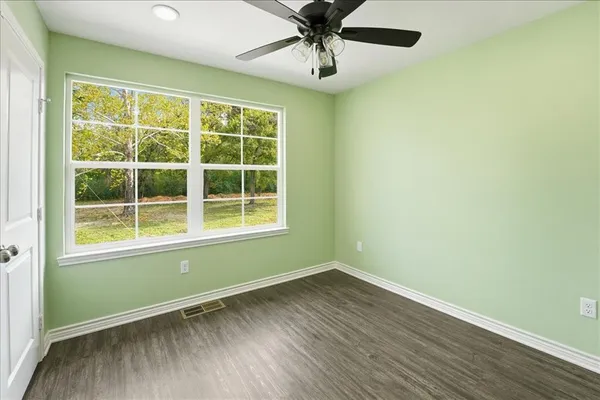 a view of an empty room with a window and wooden floor