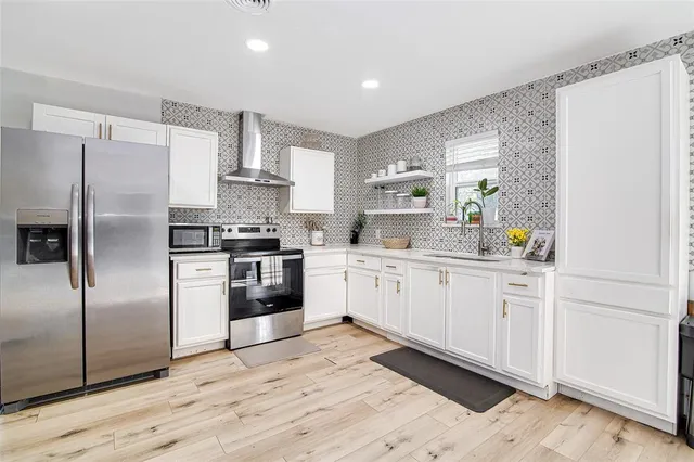 a kitchen with cabinets stainless steel appliances and a window