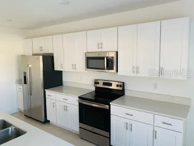 a kitchen with white cabinets and stainless steel appliances