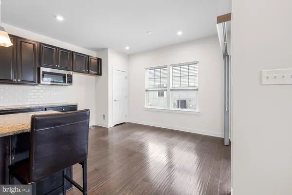 a kitchen with stainless steel appliances granite countertop a stove a refrigerator a sink a dining table and chairs with wooden floor