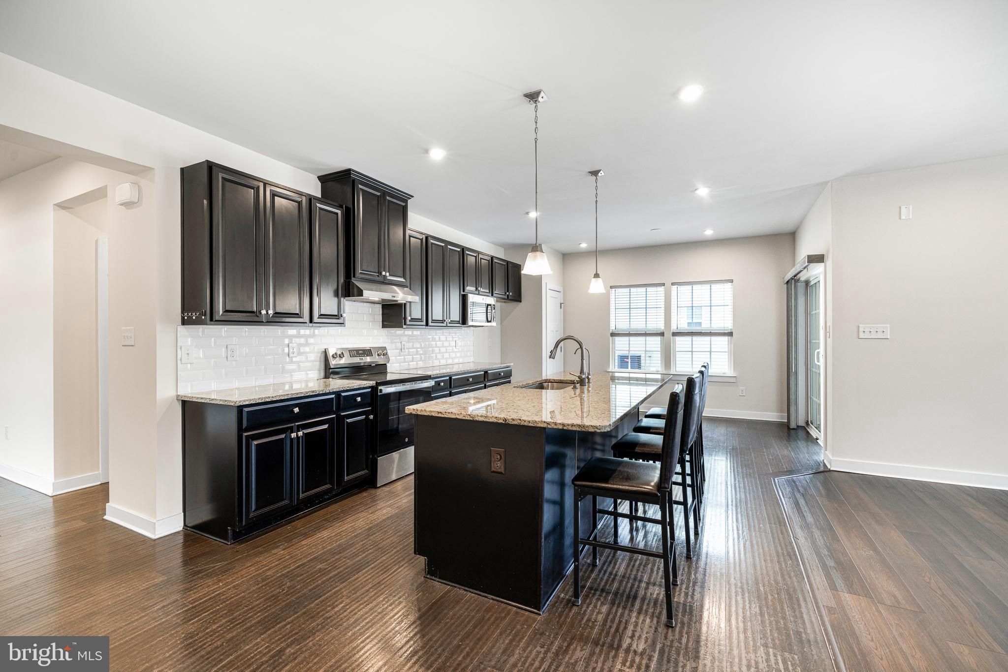 929 Robinson Road Townsend, DE 19734 - Photo 15 of 57 a kitchen with stainless steel appliances granite countertop a stove a refrigerator a sink a dining table and chairs with wooden floor