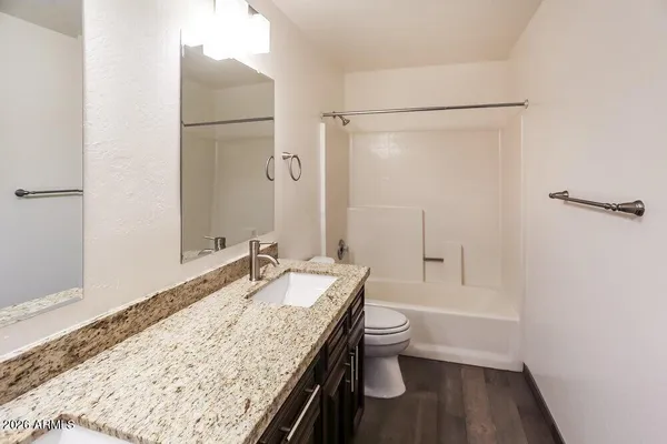 a bathroom with a granite countertop sink a toilet and shower