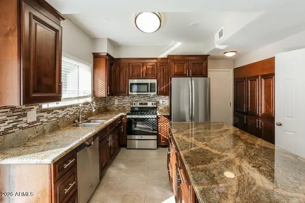 a large kitchen with granite countertop a stove refrigerator and cabinets