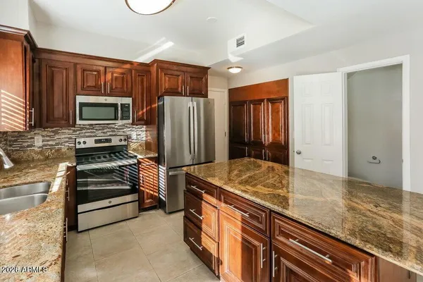 a kitchen with stainless steel appliances granite countertop a refrigerator and a stove top oven