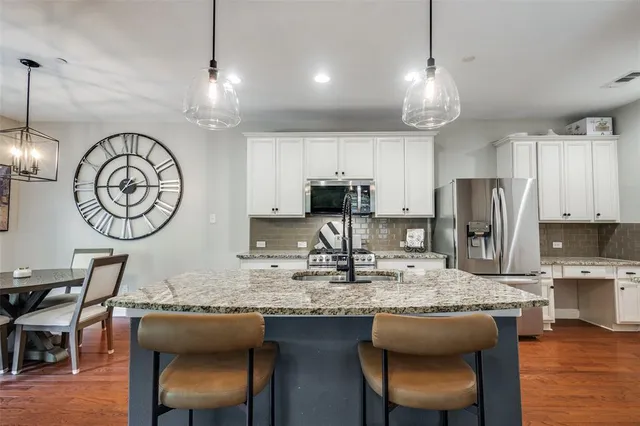 a kitchen with kitchen island granite countertop a table chairs a stove a sink and a refrigerator