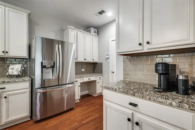 a kitchen with granite countertop a refrigerator sink and cabinets