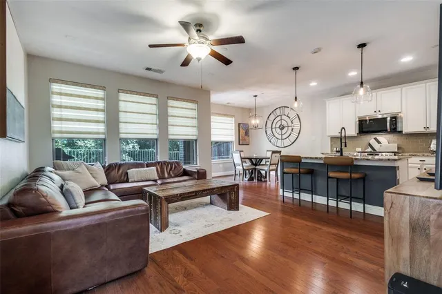 a living room with couch kitchen view and a large window