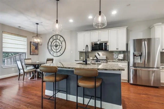 a kitchen with granite countertop a table chairs a sink a window and stainless steel appliances